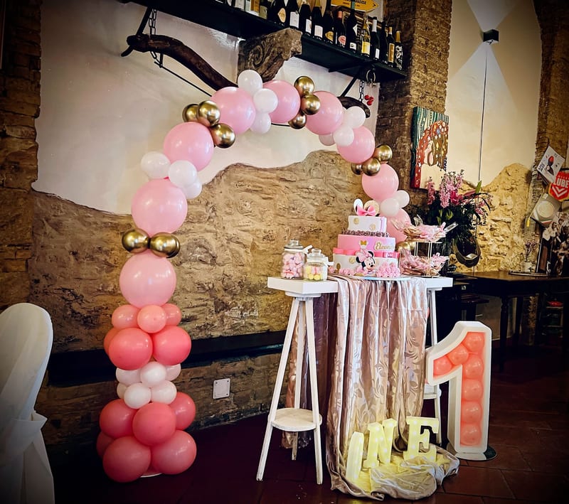 Tavolo dolci per primo compleanno con arco di palloncini rosa, pesca e oro