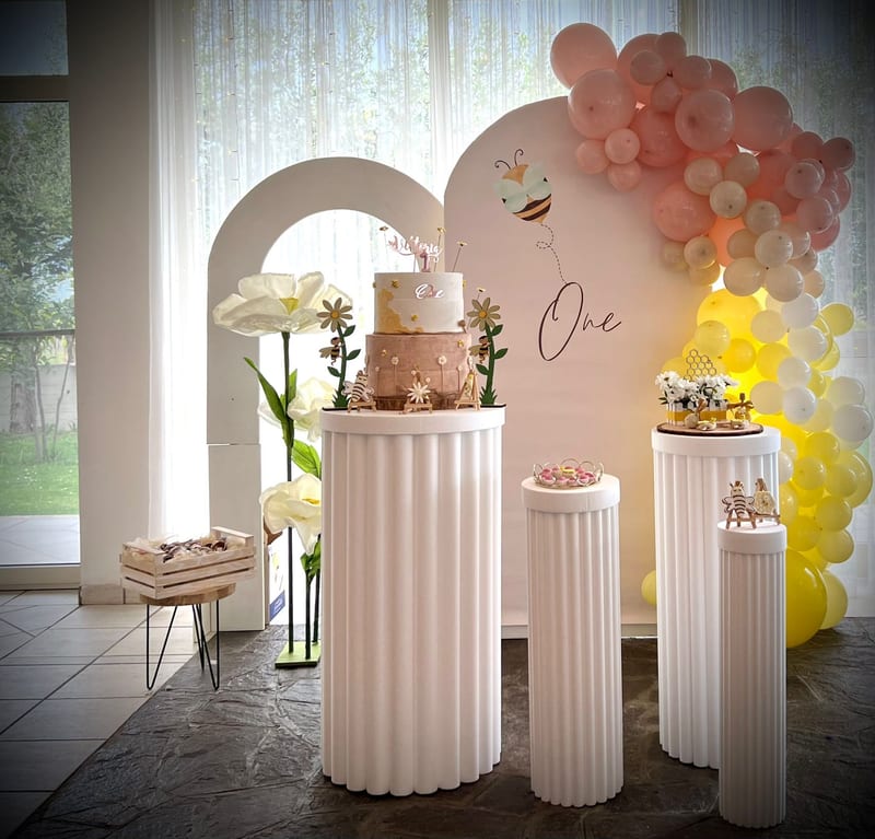 Torta a piani su colonne bianche con arco di palloncini pesca e verde salvia
