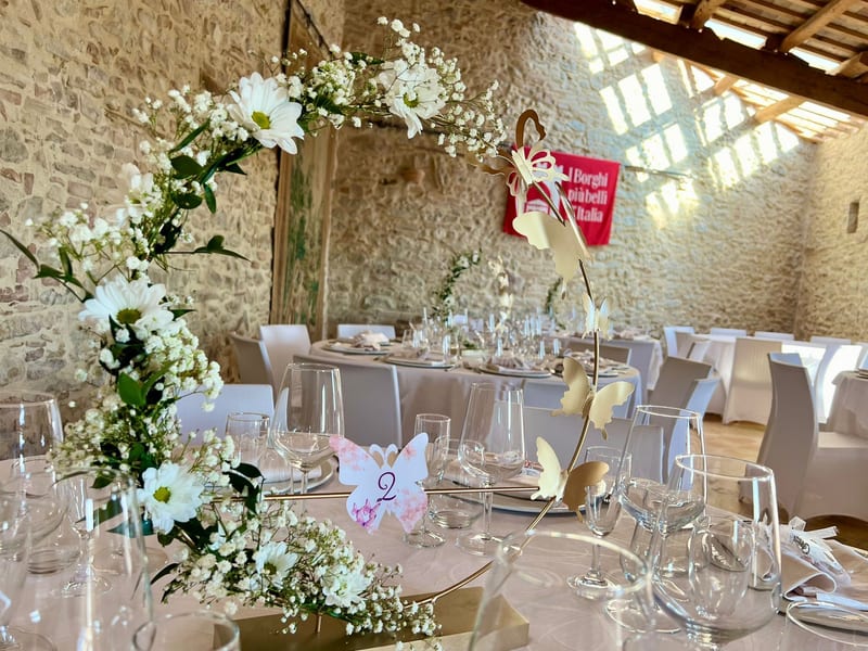 Sala per matrimonio in casale di pietra con allestimento floreale bianco e verde