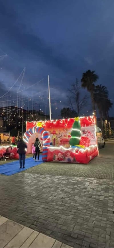 Villaggio di Natale gonfiabile illuminato di sera, con luminarie e albero addobbato