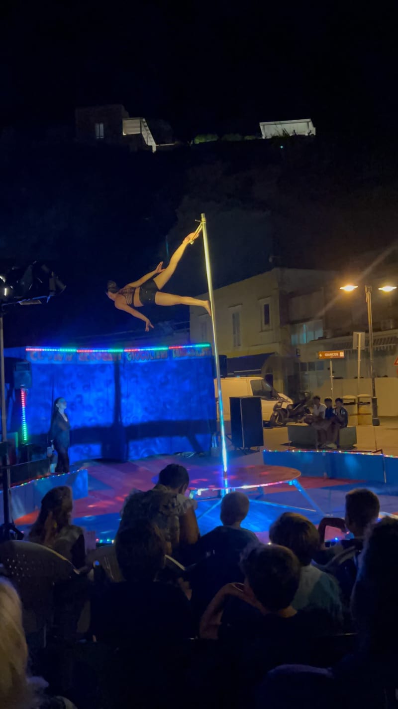 Spettacolo di acrobatica aerea su tessuti, illuminato di blu, in piazza