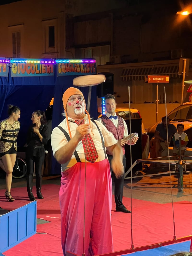 Clown giocoliere fa girare un piatto in equilibrio durante lo spettacolo serale