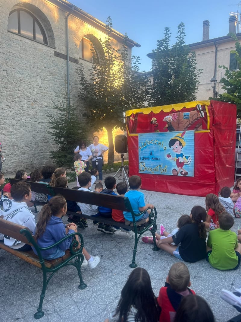 Spettacolo di burattini di Pinocchio con bambini seduti davanti al teatrino
