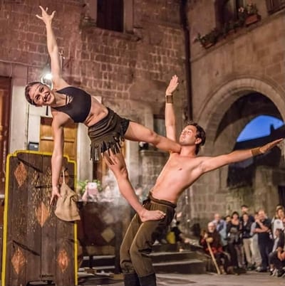 Coppia di acrobati in una figura di mano a mano davanti al pubblico nel centro storico
