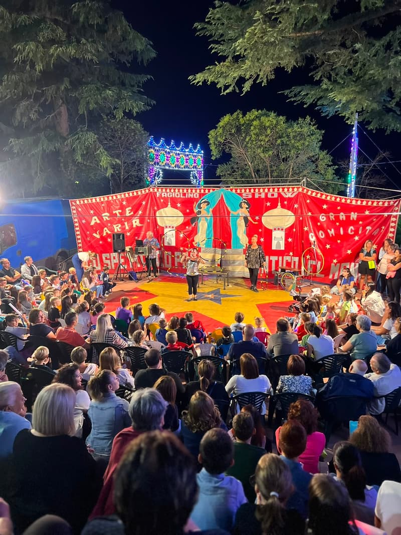 Spettacolo circense serale con il pubblico che riempie la piazza